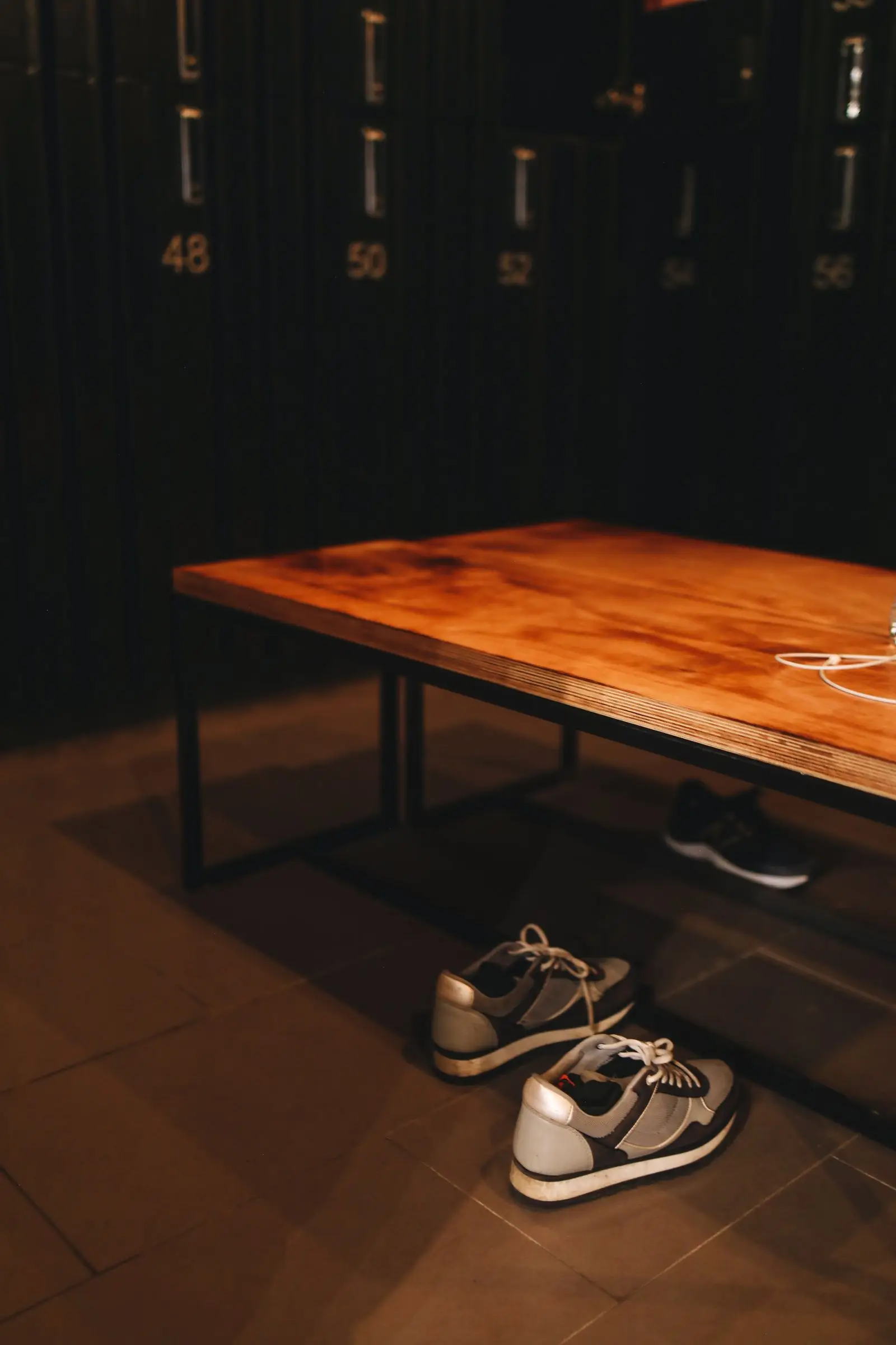 Training shoes and a bag pushed under the bench by the rack