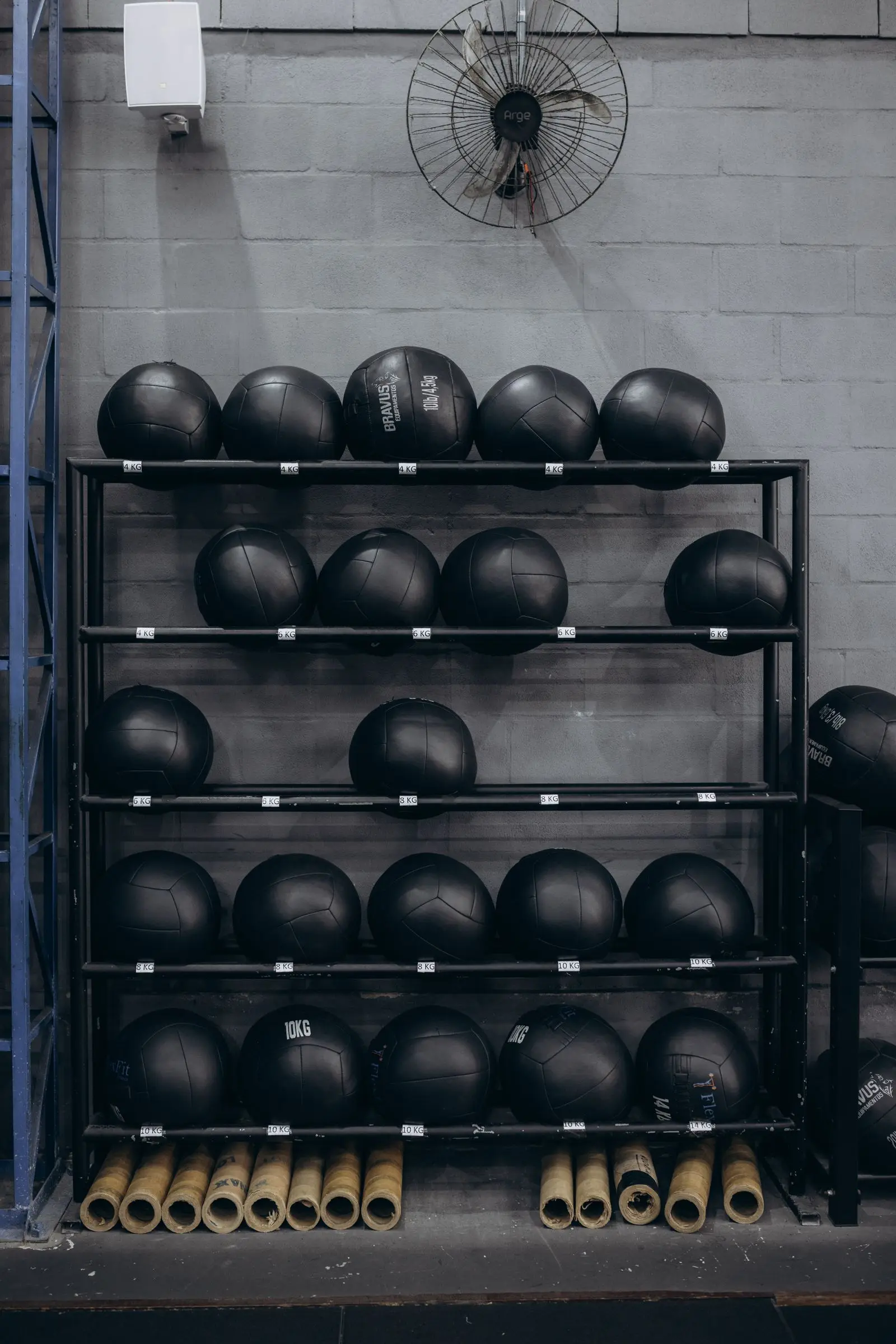 Medicine balls stored in a rack against a concrete wall